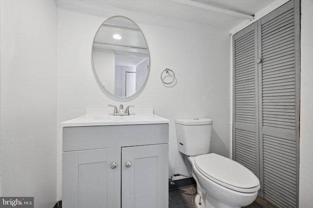 half bath with a closet, vanity, and toilet