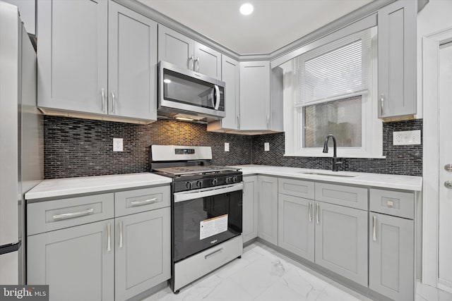 kitchen with appliances with stainless steel finishes, marble finish floor, light countertops, and a sink