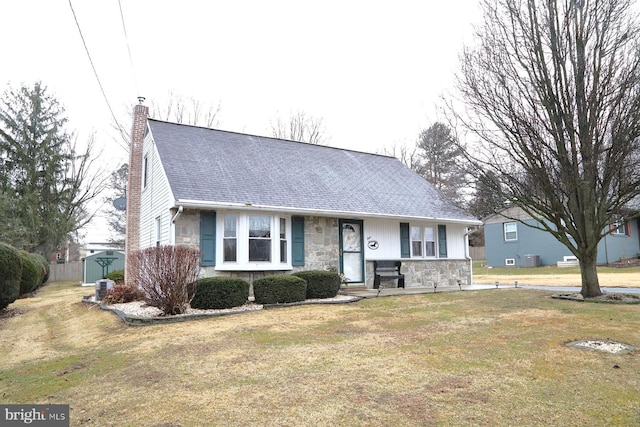 ranch-style home with stone siding, a chimney, an outbuilding, a shed, and a front yard