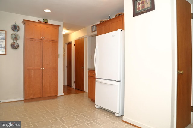 kitchen featuring brown cabinetry, recessed lighting, freestanding refrigerator, and baseboards