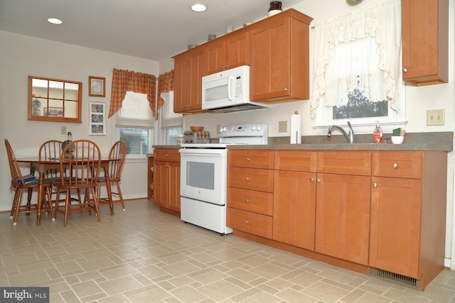 kitchen with recessed lighting, white appliances, a sink, baseboards, and brown cabinetry