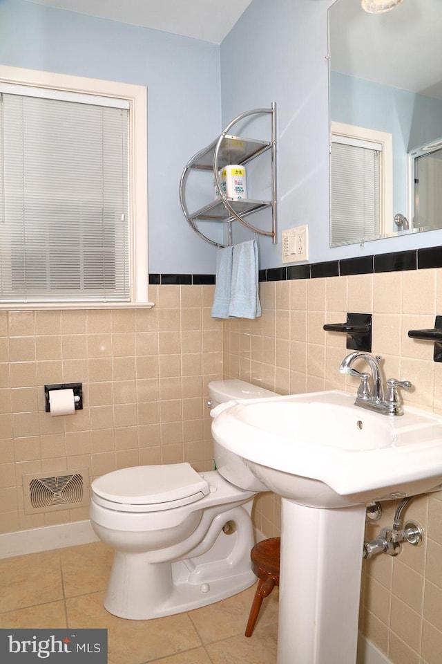 bathroom featuring toilet, visible vents, tile walls, wainscoting, and tile patterned floors