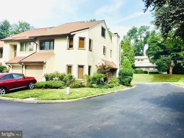 view of front facade with a chimney, a front lawn, and stucco siding