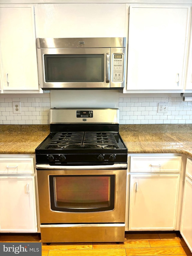 kitchen featuring white cabinetry, appliances with stainless steel finishes, and tasteful backsplash