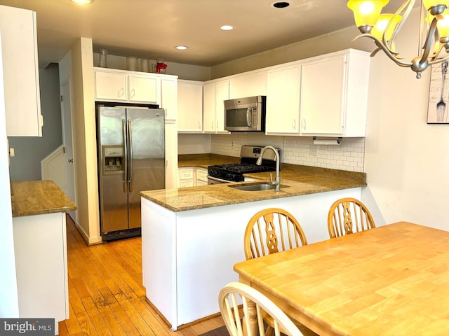 kitchen featuring a peninsula, light wood-style floors, stainless steel appliances, and decorative backsplash