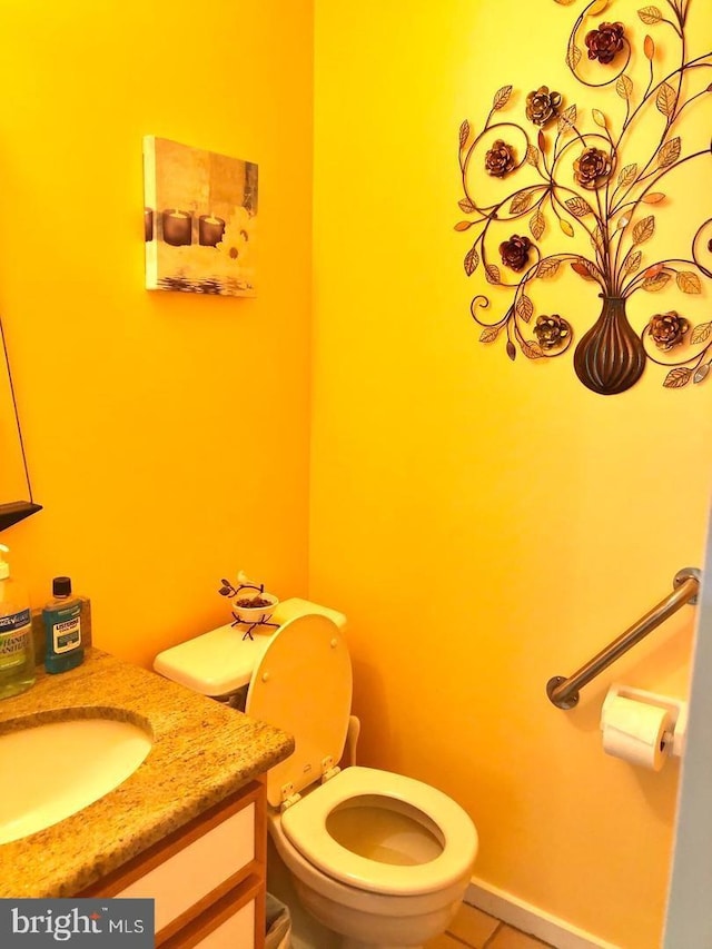 half bathroom with toilet, tile patterned floors, and vanity