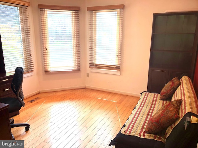 office space featuring baseboards, visible vents, and light wood-style floors