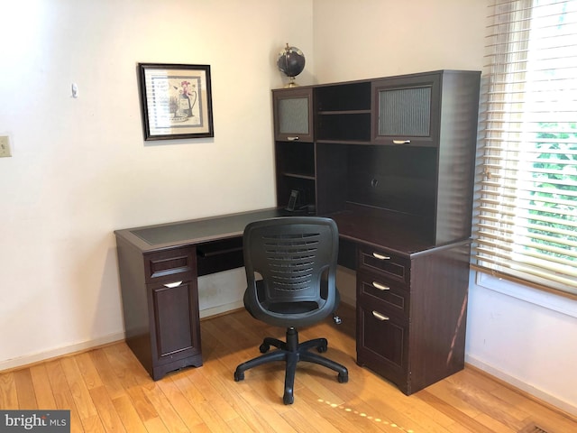 office space with baseboards, light wood finished floors, and a healthy amount of sunlight