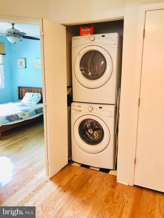 laundry area featuring laundry area, light wood-style flooring, stacked washer and clothes dryer, and a ceiling fan