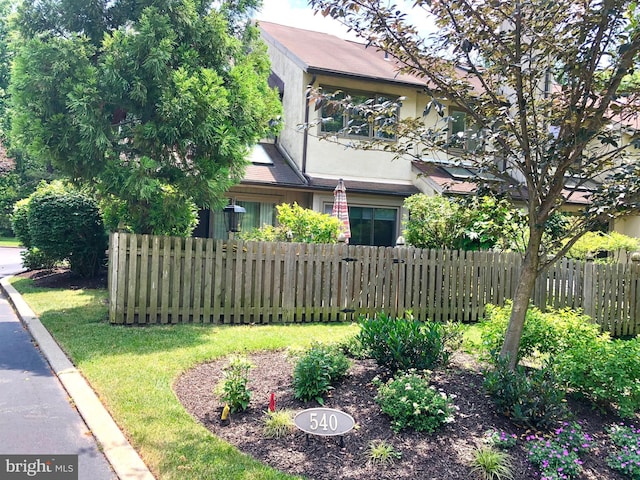 view of front of property featuring fence, a front lawn, and stucco siding