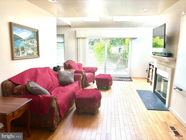 living room with hardwood / wood-style floors, a fireplace with flush hearth, and visible vents