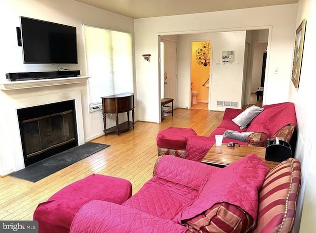 living area with a glass covered fireplace, visible vents, and hardwood / wood-style flooring