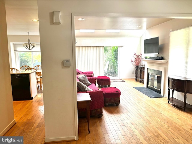 living area with an inviting chandelier, a fireplace with flush hearth, hardwood / wood-style flooring, and a healthy amount of sunlight