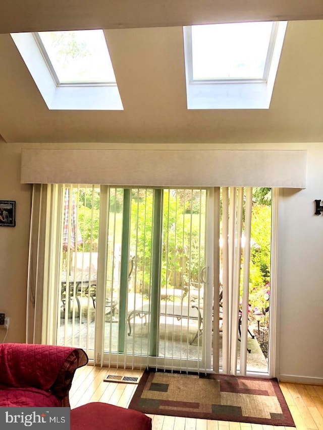 doorway featuring lofted ceiling with skylight, a healthy amount of sunlight, and hardwood / wood-style flooring