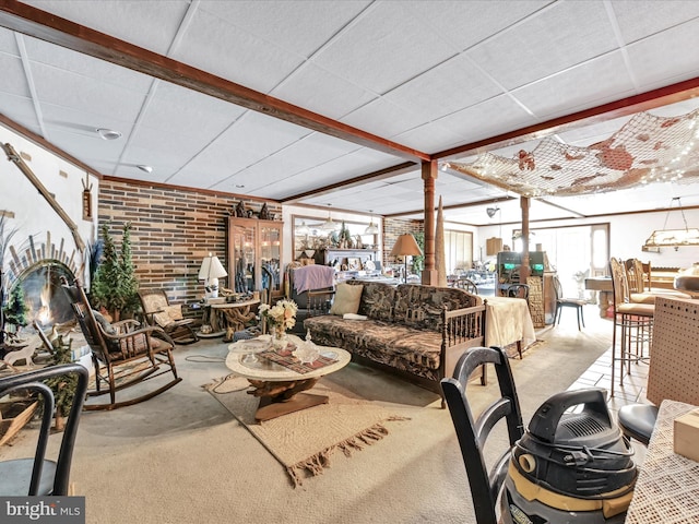 living area featuring a paneled ceiling, carpet, and brick wall