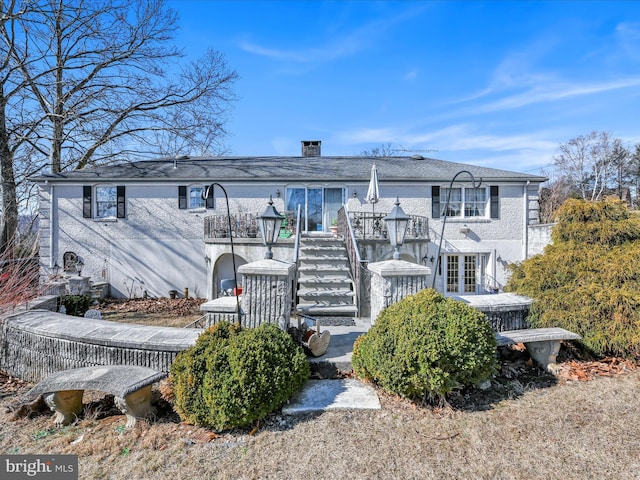 view of front of house featuring a chimney, a wooden deck, and stairs