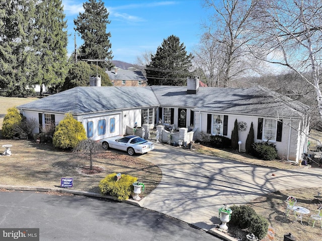 single story home featuring concrete driveway and a chimney