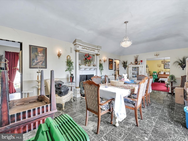 dining area with a chandelier, marble finish floor, and a fireplace