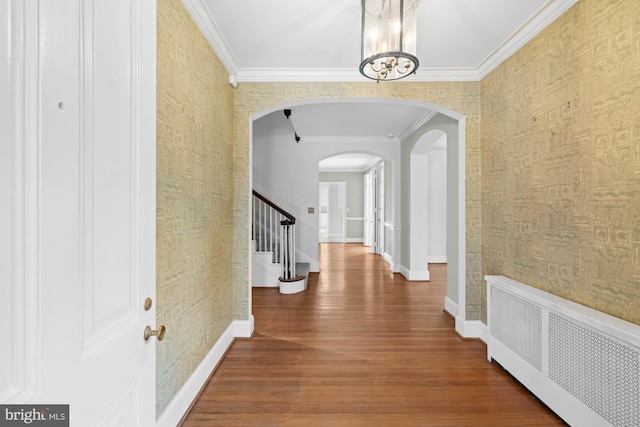 interior space with radiator, wallpapered walls, baseboards, and arched walkways