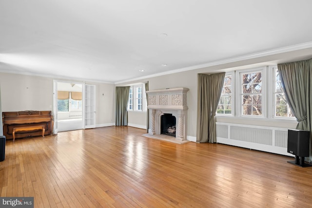 unfurnished living room featuring ornamental molding, a fireplace with raised hearth, light wood-style flooring, and radiator heating unit