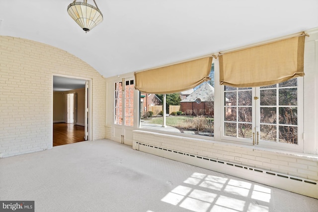 spare room with brick wall, vaulted ceiling, and baseboard heating