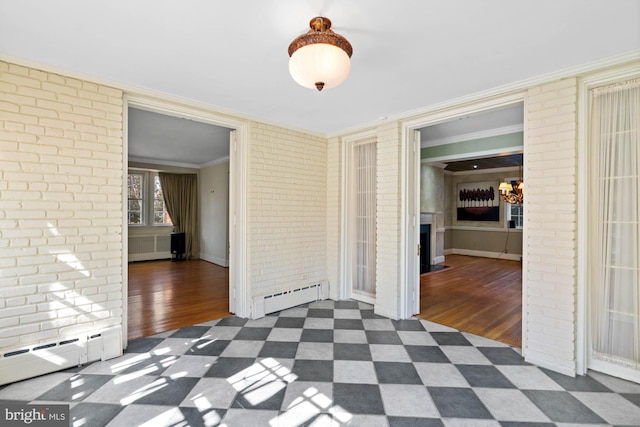 spare room with a baseboard heating unit, brick wall, ornamental molding, and dark wood-style floors