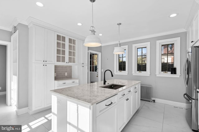 kitchen with crown molding, radiator heating unit, freestanding refrigerator, white cabinetry, and a sink