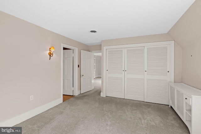 unfurnished bedroom with visible vents, baseboards, vaulted ceiling, a closet, and carpet