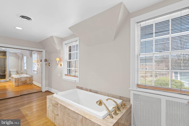 full bath featuring a bath, plenty of natural light, wood finished floors, and visible vents