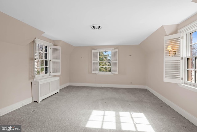 unfurnished room with carpet flooring, radiator, visible vents, and baseboards