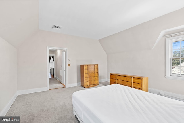 bedroom with lofted ceiling, visible vents, light carpet, and baseboards