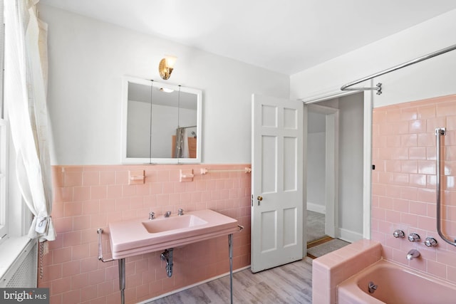 bathroom featuring a wainscoted wall, tile walls, and wood finished floors