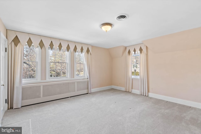 spare room featuring lofted ceiling, carpet floors, visible vents, and baseboards