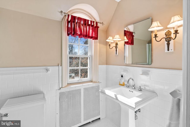 bathroom featuring radiator, vaulted ceiling, tile walls, and wainscoting