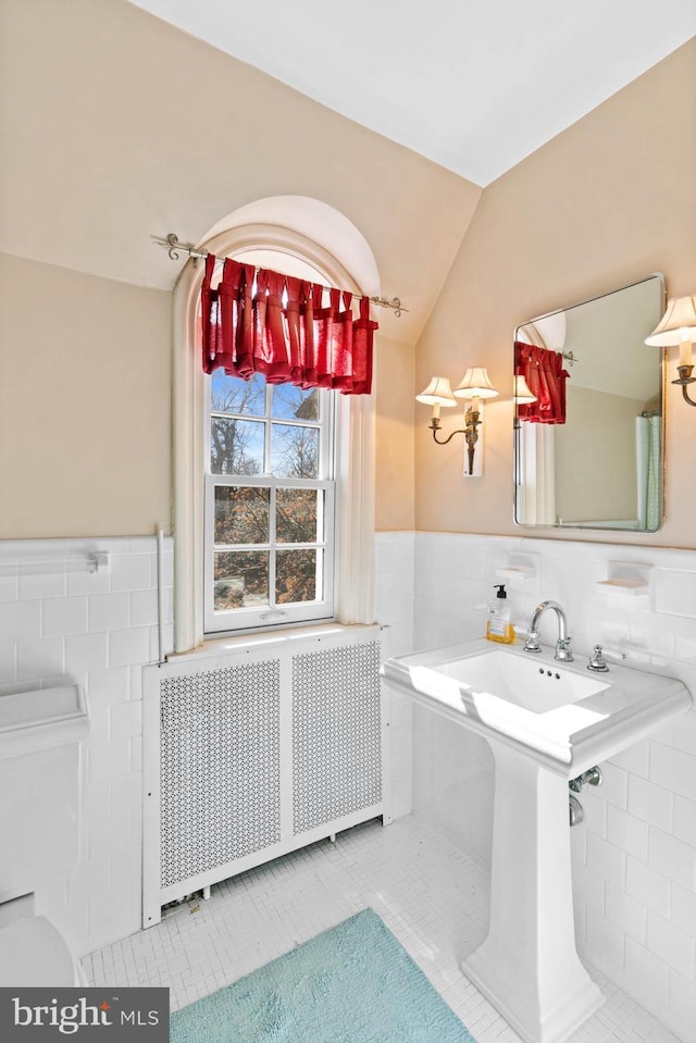 bathroom featuring vaulted ceiling, radiator heating unit, tile walls, and tile patterned floors