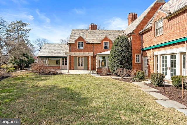 view of front of home featuring a high end roof, french doors, brick siding, and a front yard