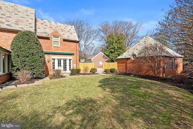 view of yard featuring french doors, an outdoor structure, and fence