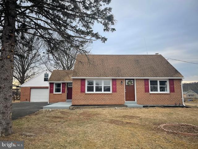 view of front of property featuring aphalt driveway, an attached garage, brick siding, a shingled roof, and a front yard