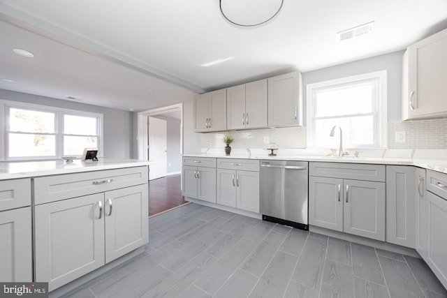 kitchen with visible vents, dishwasher, a sink, and decorative backsplash