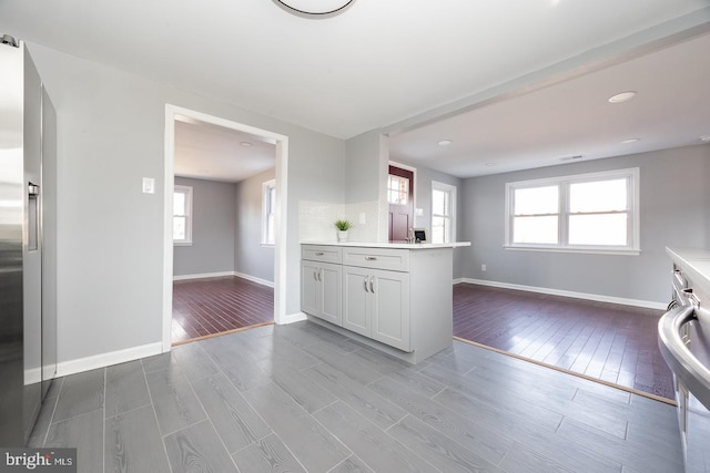 kitchen featuring wood tiled floor, baseboards, light countertops, and stainless steel fridge with ice dispenser