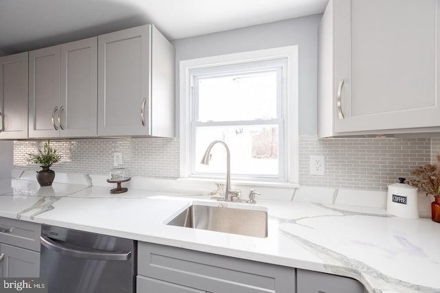 kitchen featuring stainless steel dishwasher, gray cabinets, and a sink