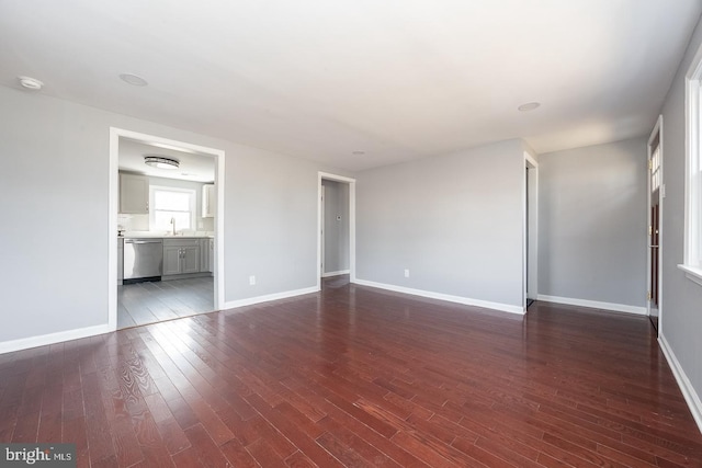 interior space with dark wood finished floors, a sink, and baseboards