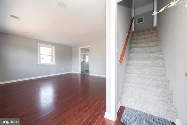 staircase featuring visible vents, baseboards, and wood finished floors