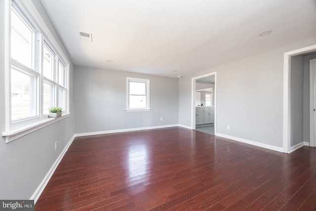 spare room featuring baseboards, visible vents, and dark wood-type flooring