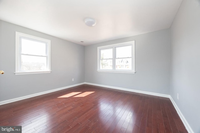 spare room with baseboards, dark wood finished floors, and a wealth of natural light