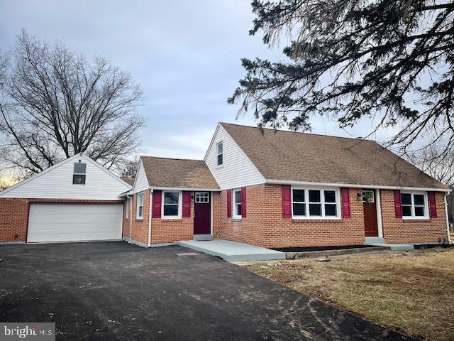 view of front of property with a garage, roof with shingles, an outdoor structure, and brick siding