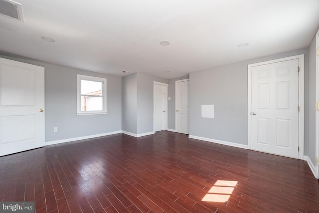 empty room with baseboards, visible vents, and wood finished floors