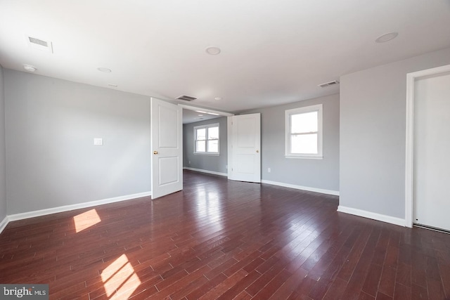 spare room featuring baseboards, visible vents, and wood finished floors