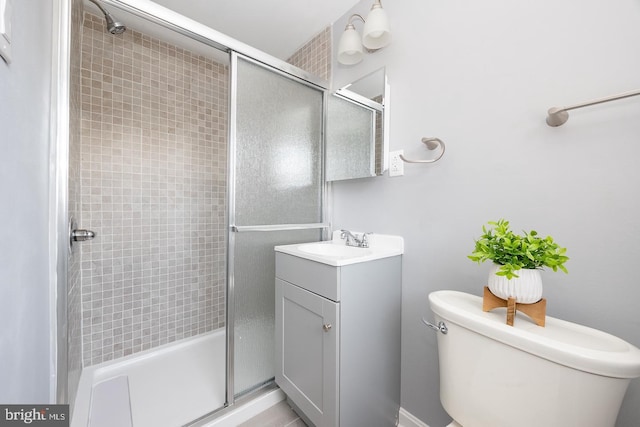 bathroom featuring vanity, a shower stall, and toilet