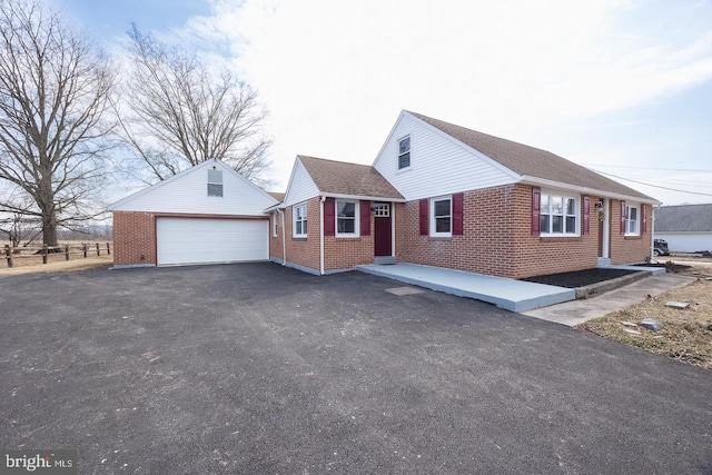 view of front of house with a garage, brick siding, an outdoor structure, and roof with shingles